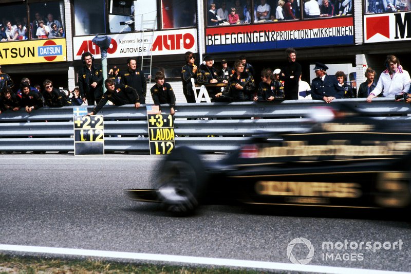 Mario Andretti schiet over het rechte stuk, terwijl zijn team toekijkt.
