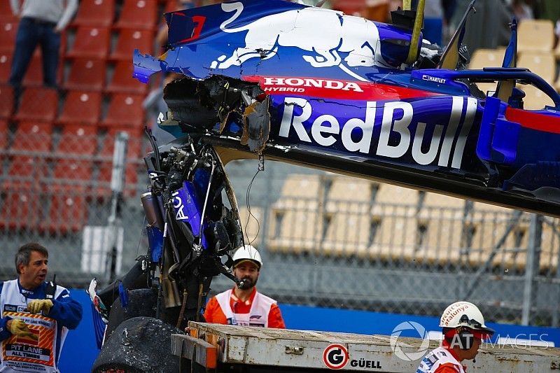 Oficiales retiran el automóvil dañado de Brendon Hartley, Toro Rosso STR13, del circuito cuando la caja de cambios cuelga de la parte posterior