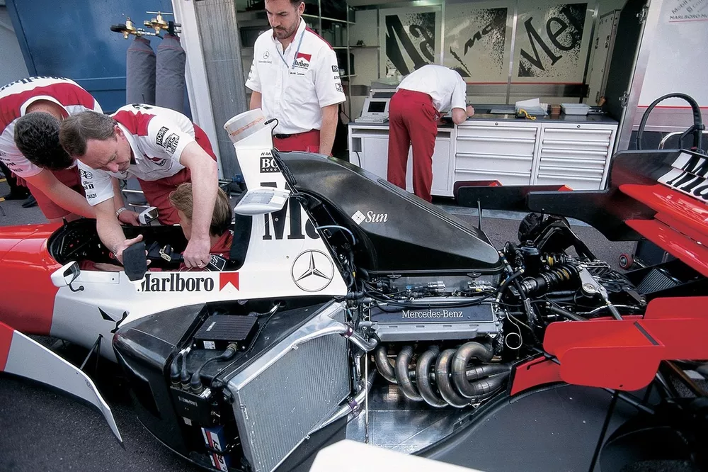McLaren mechanics strap Mika Hakkinen into his MP4-10 Mercedes in the garage
