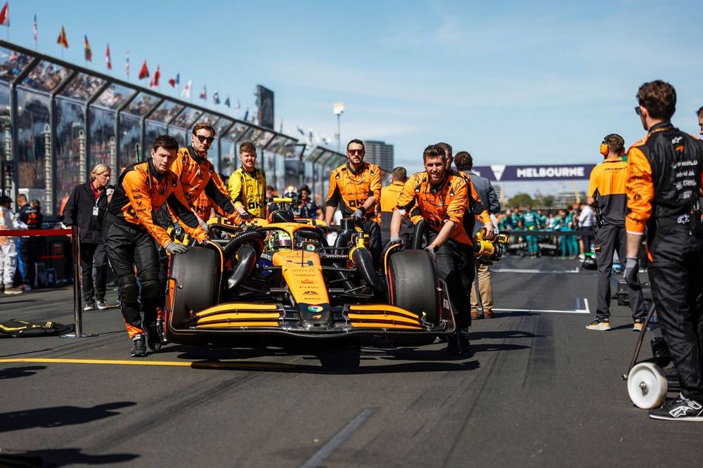 Mechanics of the McLaren F1 Team push the car of Lando Norris, McLaren MCL38, to its grid spot