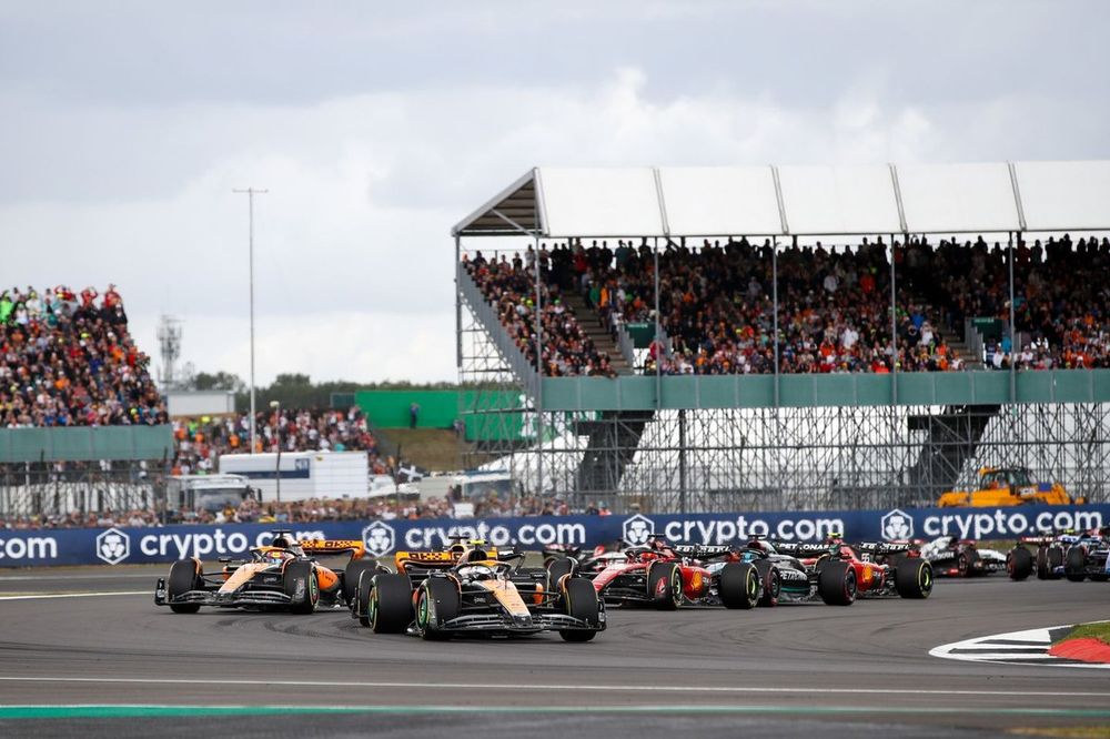 Lando Norris, McLaren MCL60, Max Verstappen, Red Bull Racing RB19, Oscar Piastri, McLaren MCL60, y el resto de la parrilla en la primera vuelta