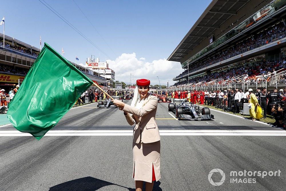 Une hôtesse de l'air Emirates agite un drapeau vert sur la grille