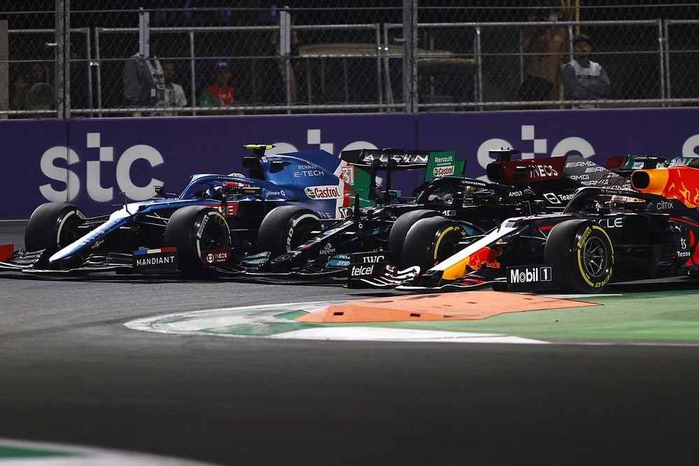 Max Verstappen, Red Bull Racing RB16B, Lewis Hamilton, Mercedes W12, and Esteban Ocon, Alpine A521, battle for the lead at the restart