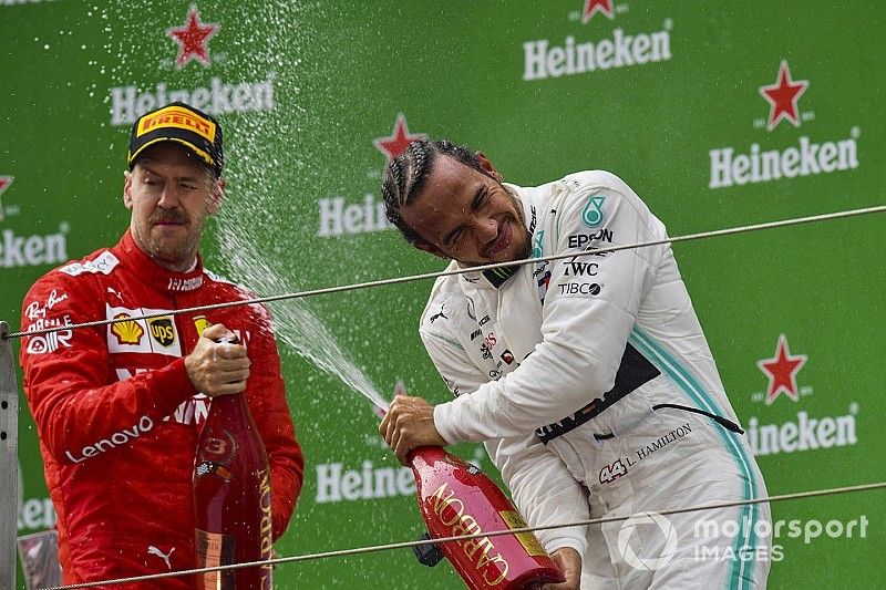 Sebastian Vettel, Ferrari, 3rd position, and Lewis Hamilton, Mercedes AMG F1, 1st position, celebrate with Champagne on the podium