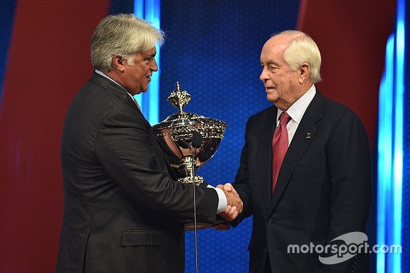 Roger Penske receives the champion's trophy from IndyCar CEO Mark Miles