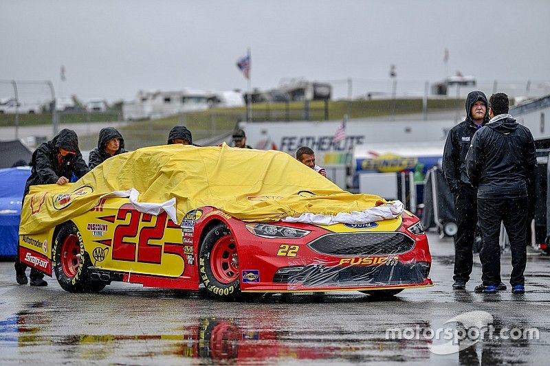 El auto de Joey Logano, Team Penske, Ford Fusion Shell Pennzoil, es empujado en el área de garajes bajo la lluvia.