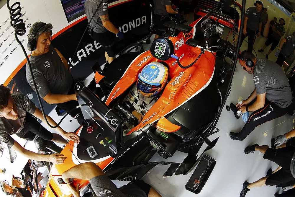 Fernando Alonso, McLaren, es atendido por mec&aacute;nicos en su garaje