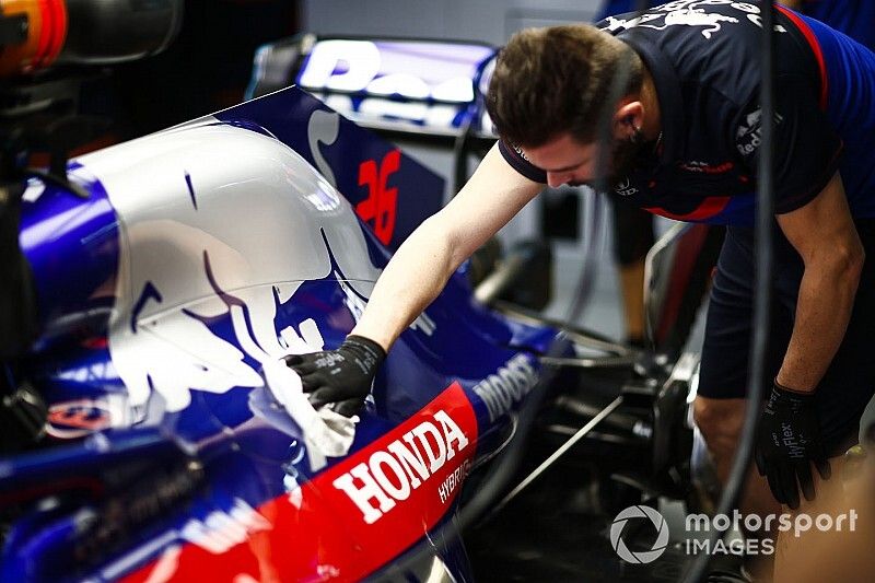 A Toro Rosso mechanic wipes down an engine cover