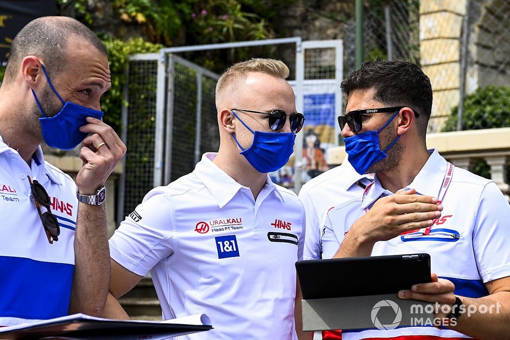 A Ferrari passes as Nikita Mazepin, Haas F1, walks the track with his team