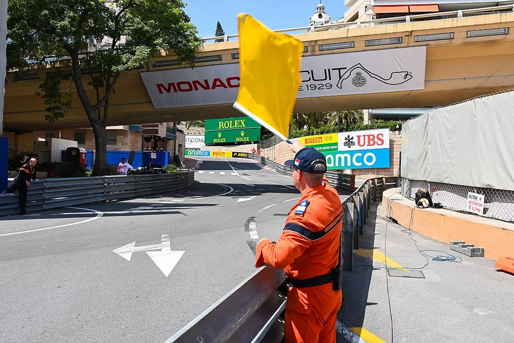 Un commissaire avec un drapeau jaune dans le virage du Portier