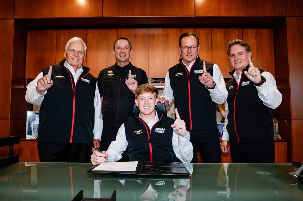 Connor Zilisch signs with Hendrick Motorsports, pictured with Rick Hendrick, Chad Knaus, Jeff Andrews, and Jeff Gordon