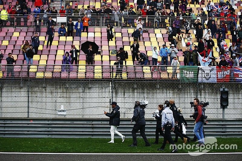 Lewis Hamilton, Mercedes AMG, gives caps to fans during a weather delay in FP2