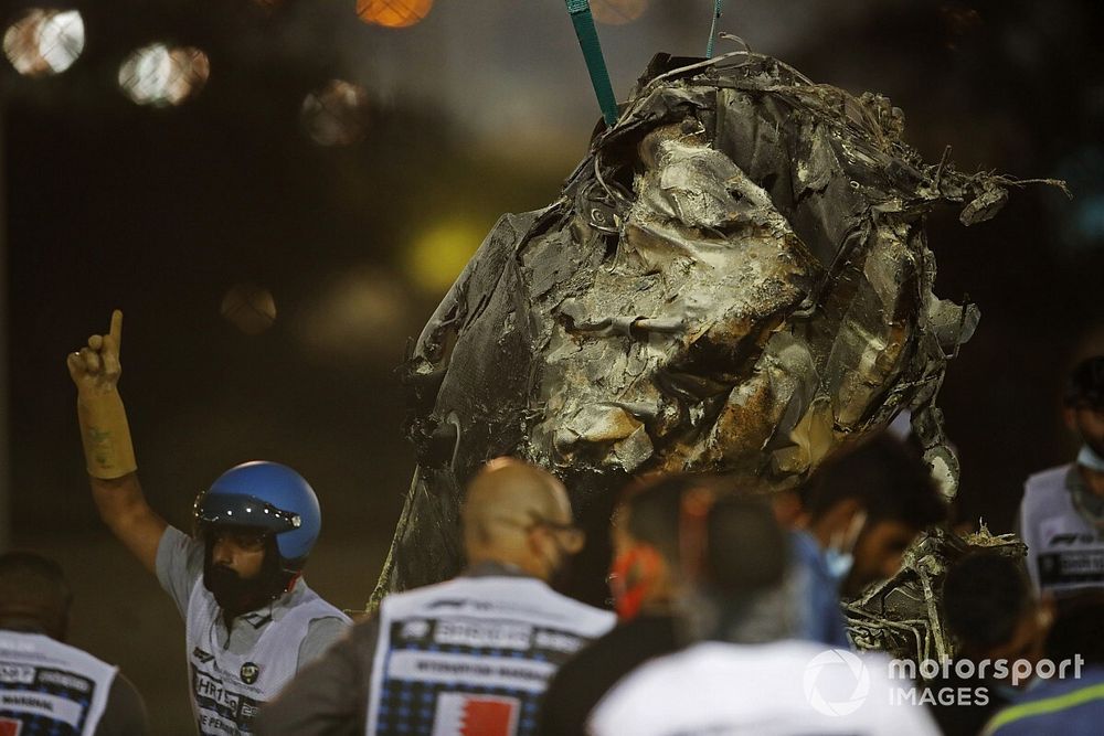 The charred wrecked remains of the Romain Grosjean Haas VF-20 is cleared by marshals after a horrendous opening lap crash at the Bahrain Grand Prix