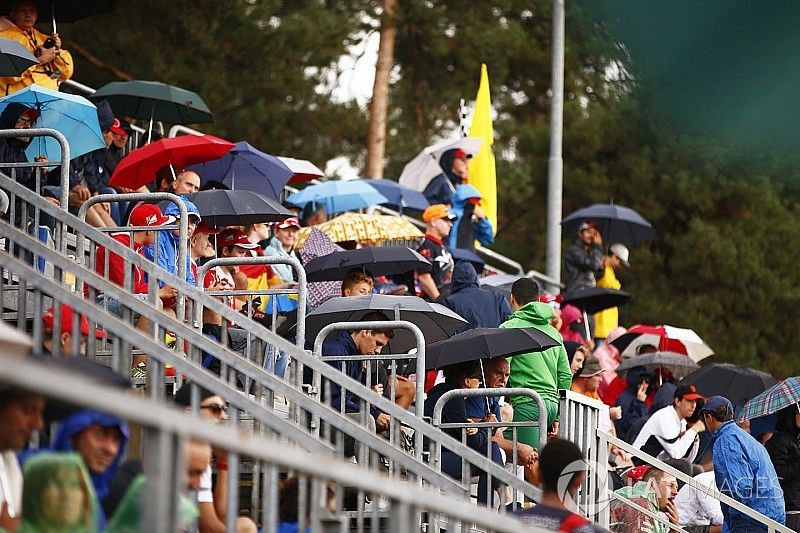  Fans take cover from the rain under umbrellas in the grandstand