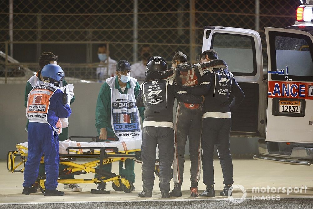 Romain Grosjean, Haas F1, is assisted by medical delegates and marshals after a big crash on the opening lap