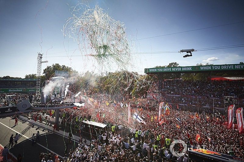 Personal de equipo de Mercedes y una multitud de fans de Ferrari se reúnen para el podio