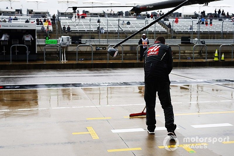 A Haas F1 mechanic dries the pit box with a brush.