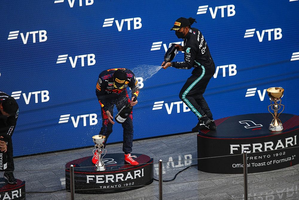 Lewis Hamilton, Mercedes, 1st position, sprays Max Verstappen, Red Bull Racing, 2nd position, with Champagne on the podium