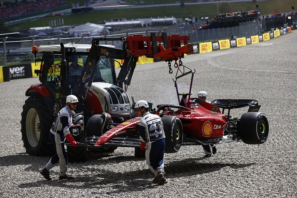 Marshals bergen de door brand beschadigde auto van Carlos Sainz, Ferrari F1-75