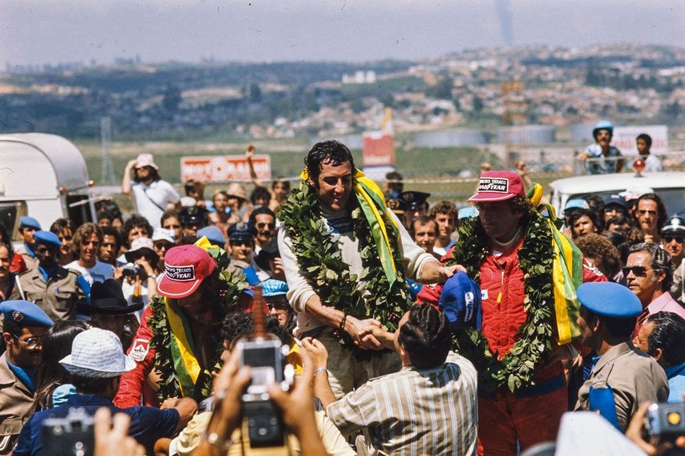 Carlos Pace celebrates his first and only victory in front of his home crowd with fellow Brazilian Emerson Fittipaldi, 2nd position, and Jochen Mass, 3rd position