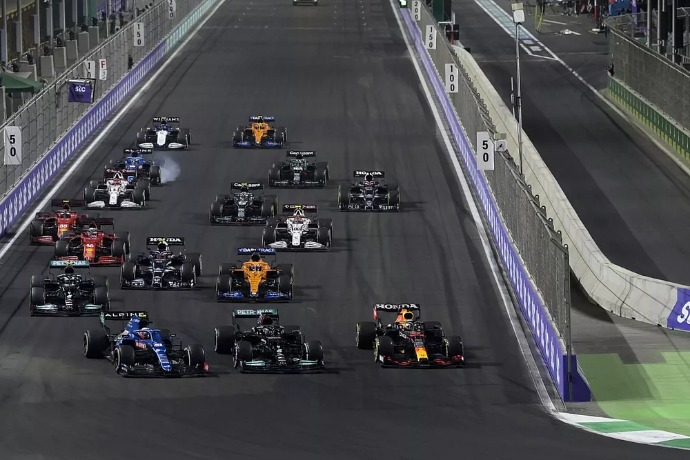 Max Verstappen, Red Bull Racing RB16B, Lewis Hamilton, Mercedes W12, and Esteban Ocon, Alpine A521, battle for the lead at the restart