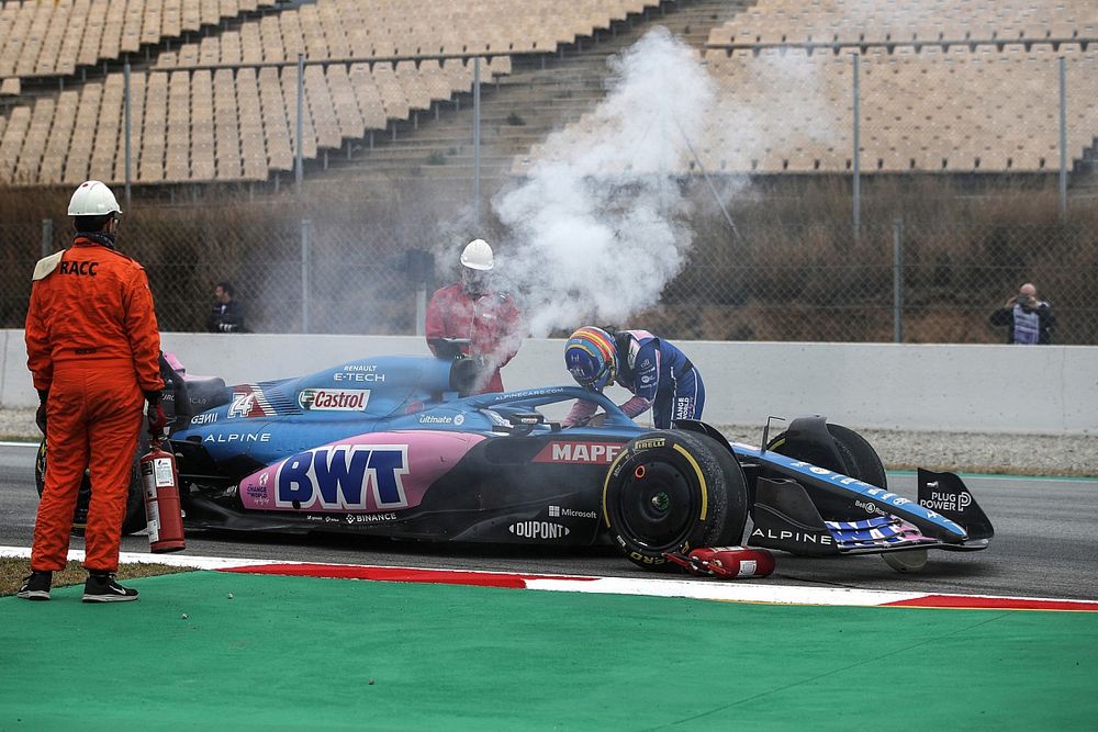Marshals assist as Fernando Alonso, Alpine A522, stops with technical issues as smoke rises from the car