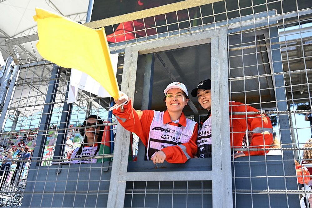 Oficiales de pista agitan una bandera amarilla