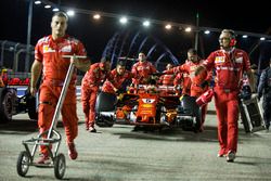 El coche de Sebastian Vettel, Ferrari SF70H, es empujado por miembros del equipo.