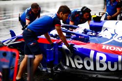 Monteurs duwen de wagen van Pierre Gasly Toro Rosso STR13 Honda in de garage