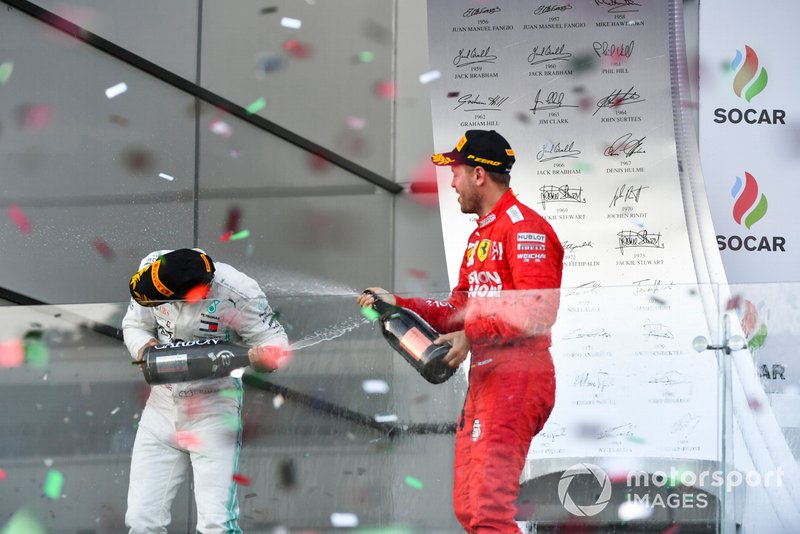 Lewis Hamilton, Mercedes AMG F1, 2nd position, and Sebastian Vettel, Ferrari, 3rd position, spray Champagne at each other on the podium