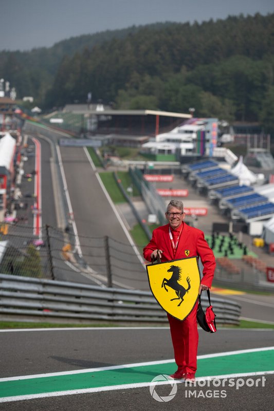 A man carries a Ferrari logo at Eau Rouge
