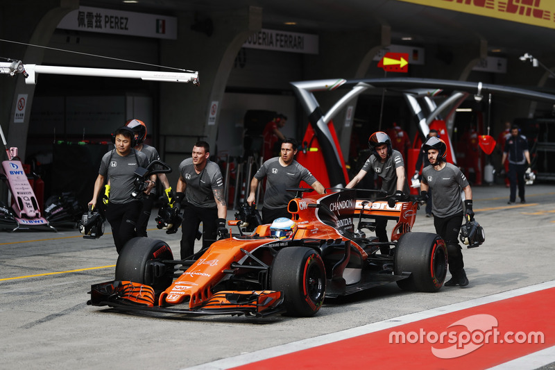 The McLaren team return Fernando Alonso, McLaren MCL32, to the garage