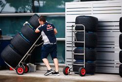 A Red Bull team member wheels a stack of Pirelli tyres