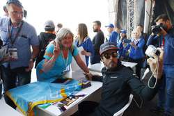 Fernando Alonso, McLaren, takes a picture for a fan