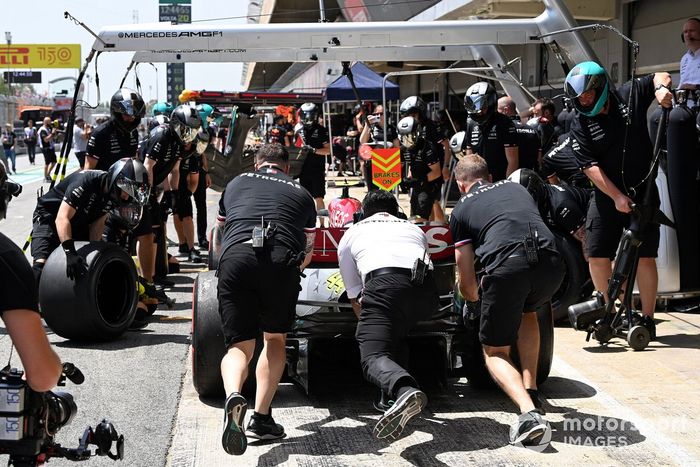 Los mecánicos empujan el coche de Lewis Hamilton, Mercedes W13, en el pit lane