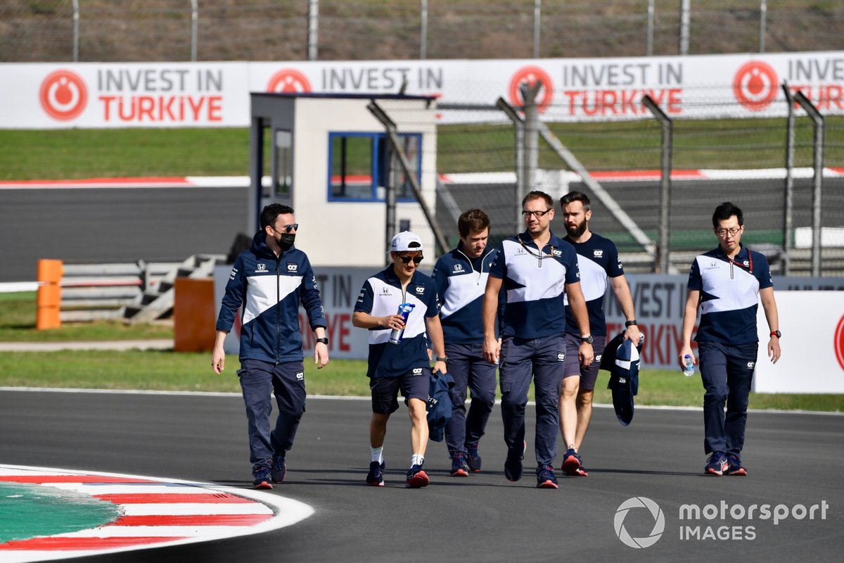 Yuki Tsunoda, AlphaTauri, walks the track with members of his team