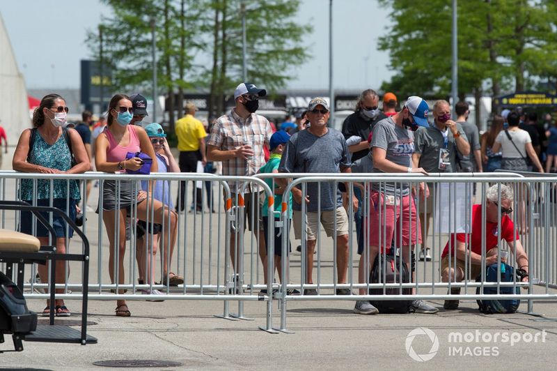 Los aficionados miran a los coches y los pilotos desde la distancia