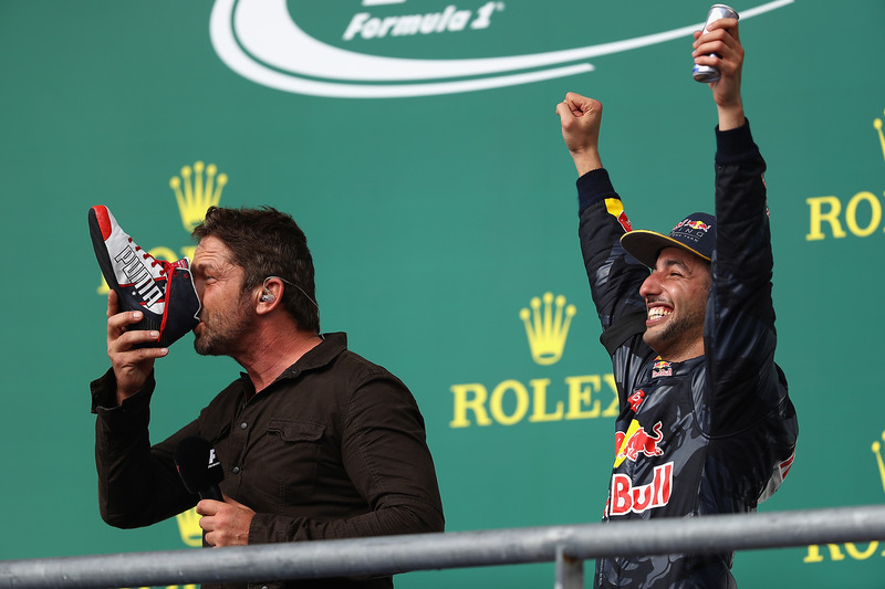 L'acteur Gerard Butler fait un shoey sur le podium avec Daniel Ricciardo, Red Bull Racing, troisième