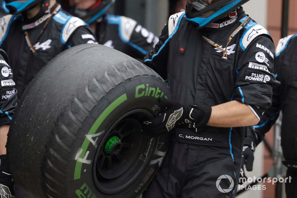 Un miembro del equipo de boxes de Alpine F1 con un neumático intermedio desgastado