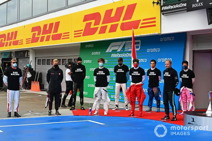 Los otros pilotos se reúnen alrededor de los trofeos antes del comienzo en apoyo de la campaña para el fin del racismo
