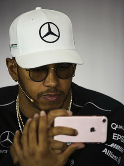 Lewis Hamilton, Mercedes AMG F1, uses his phone, in the Thursday press conference