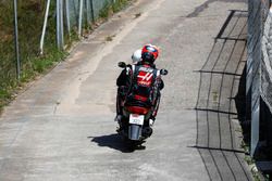 Romain Grosjean, Haas F1 Team VF-18, receives a lift back to the pits on a moped