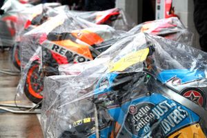 MotoGP-Bikes unter Regenplanen in der Boxengasse