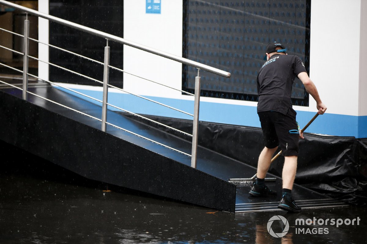 Un miembro de Williams Racing trata de achicar agua de la entrada del motorhome