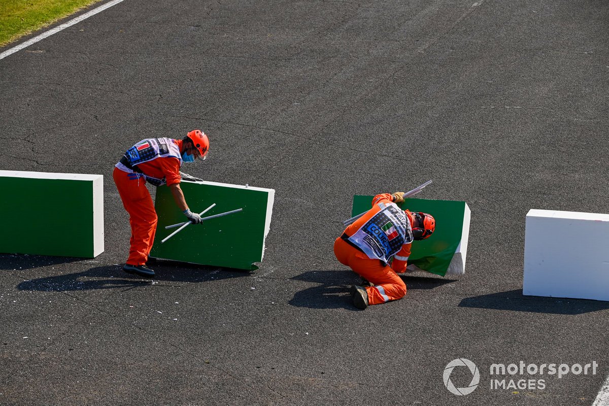 Los oficiales de pista reparan la barrera rota después de que Sebastian Vettel, el Ferrari SF1000 chocó con ella