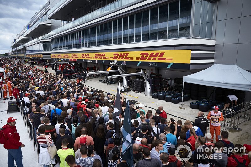 Fans in the pit lane walk outside of the AMG Mercedes garage