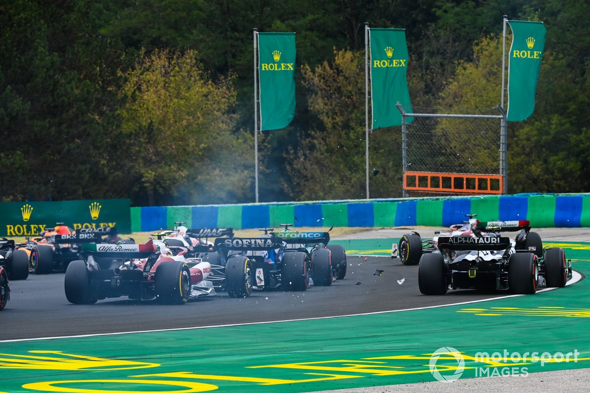 Una colisión hace volar escombros en la primera vuelta mientras Valtteri Bottas, Alfa Romeo C42, Lance Stroll, Aston Martin AMR22, Alex Albon, Williams FW44, Yuki Tsunoda, AlphaTauri AT03, Zhou Guanyu, Alfa Romeo C42, luchan por la posición