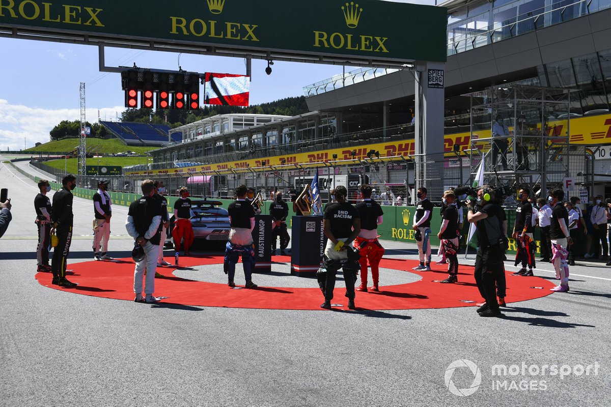 The drivers stand for the national anthems on the grid