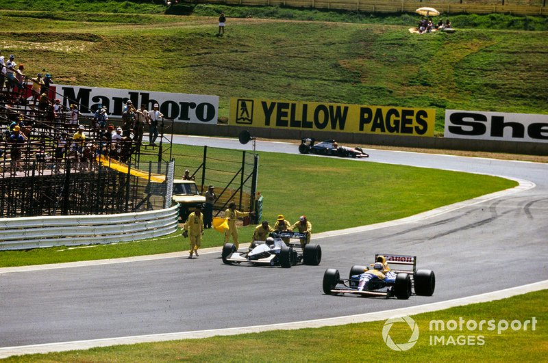 Nigel Mansell, Williams FW14B Renault, pasa junto a los comisarios que asisten el coche de Giovanna Amati, Brabham BT60B