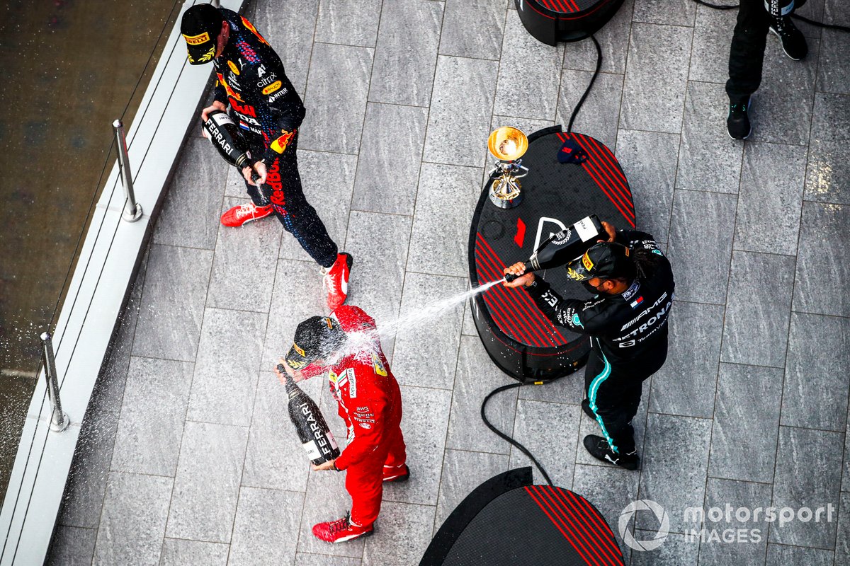 Carlos Sainz Jr., Ferrari, 3a posizione, Max Verstappen, Red Bull Racing, 2a posizione, e Lewis Hamilton, Mercedes, 1a posizione, spruzzano Champagne sul podio